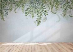 an empty room with wooden floors and a wall painted with green leaves on the wall