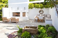 an outdoor living area with couches, chairs and fire place in the middle of it