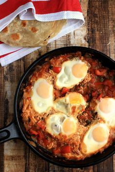 an iron skillet filled with eggs on top of a wooden table