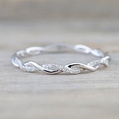 a white gold wedding band with diamonds on the side, sitting on a wooden surface