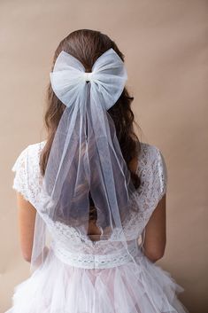 the back of a woman wearing a veil with a bow on it's head