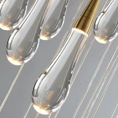 several clear glass lamps hanging from strings with a gold colored light bulb in the middle