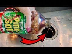 a hand is pouring water into a sink with a can of soda in the drain