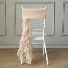 a white chair with a pink ruffled seat cover on it in front of a wall