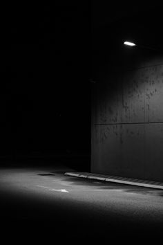 a black and white photo of a person sitting on a bench in the middle of an empty parking lot