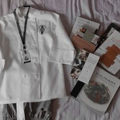 a white jacket and some books on top of a bed next to a blue lanyard