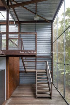 the inside of a building with stairs and glass walls on both sides, leading to an upper level balcony