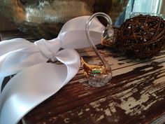 a white bow on top of a wooden table next to a vase with a ball