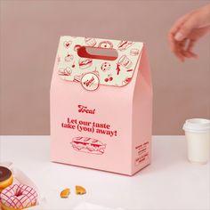 a pink paper bag sitting on top of a table next to donuts and coffee