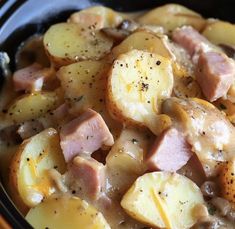 a close up of food in a bowl with potatoes and ham on top, ready to be eaten