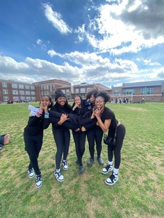 four girls standing in the grass with their arms around each other