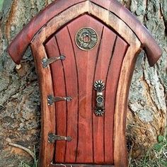 a red door sitting in the grass next to a tree