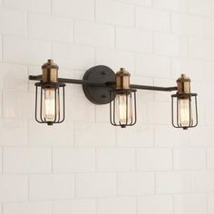 three lights are hanging on the wall next to a white brick wall in an industrial - style bathroom