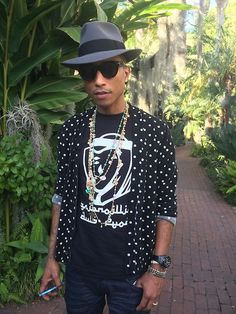 a man wearing a hat and sunglasses standing on a brick walkway