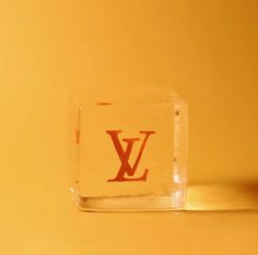 a glass block with the word louis written on it sitting on a yellow surface next to an orange wall