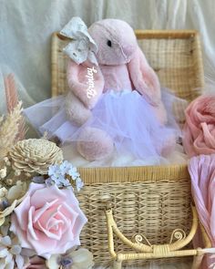 a pink teddy bear sitting in a wicker basket next to flowers and other items