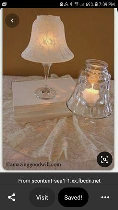 a table topped with a glass vase filled with water and a lit candle next to a book