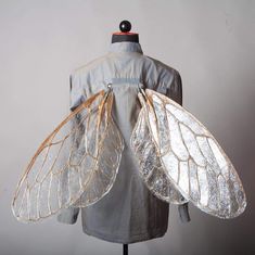 the back of a dress with wings attached to it's chest, and on top of a mannequin head