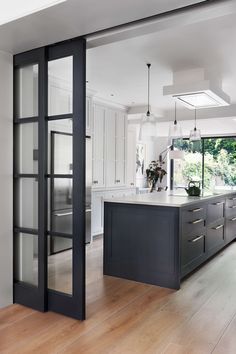 an open kitchen with white cabinets and black glass doors on the front door, along with hardwood flooring