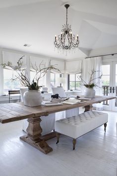 a dining room table with two benches and a chandelier hanging from the ceiling