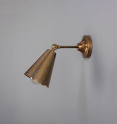 an antique brass wall light on a white wall with a gray backround background