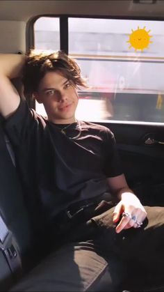 a young man sitting in the back seat of a car