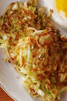 an egg is sitting on top of some hashbrowns that are on a plate