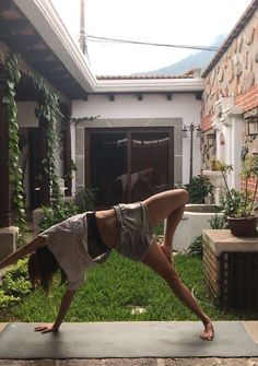 a woman is doing yoga outside in front of a house with her hands on the ground