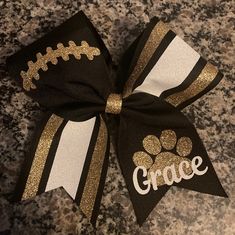 a black and gold cheer bow with the word grace on it's side sitting on a granite surface