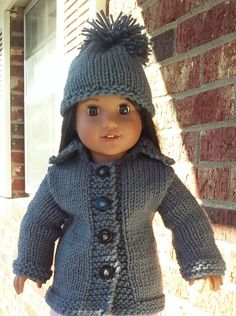 a doll wearing a gray knitted coat and hat