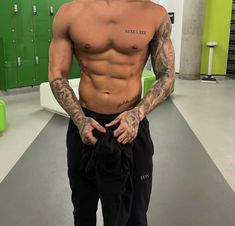 a shirtless man standing in a locker room with his hands on his hips and looking at the camera