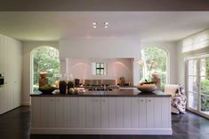 a kitchen with white cabinets and black tile flooring next to an open door leading to the outside