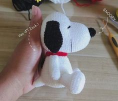 a crocheted stuffed dog is being held by someone's hand with scissors