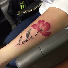 a woman's arm with a flower on it and the word love written in cursive font