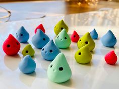 there are many different colored plastic toys in the shape of raindrops on a table