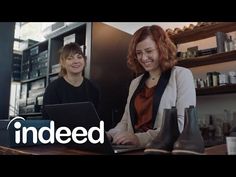 two women sitting in front of a laptop computer