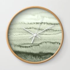 a clock that is on the side of a wall with water and grass in it