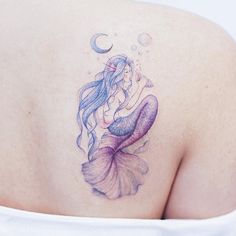 a mermaid tattoo on the back of a woman's shoulder