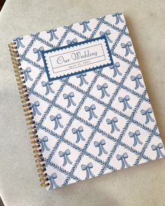 a blue and white wedding guest book with bows on it, sitting on a table