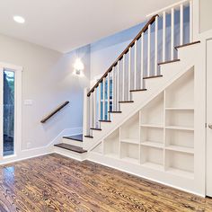 an empty living room with wood flooring and white bookcases on the wall