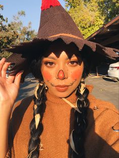 a woman with her face painted like a clown wearing a brown hat and braids