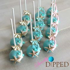 there are many blue cake pops with gold leaves on them, and one is white