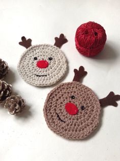 three crocheted christmas ornaments with red noses and nose on white surface next to pine cones