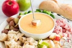 a white plate topped with lots of food and an apple next to breadsticks