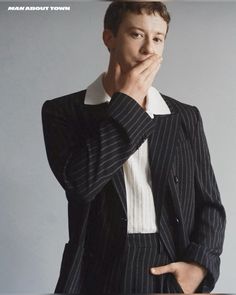 a man in a pinstripe suit is posing for a magazine cover with his hand on his chin