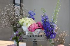 there are many different flowers in vases on the table and one is pink, purple, white and green