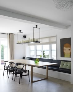 a dining room table and chairs in front of a window with a painting on the wall