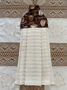 two white towels are sitting on top of a doily with coffee mugs in them