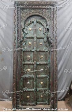 an old wooden door with ornate carvings on the front and sides, in green paint