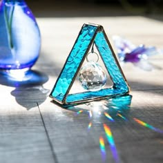 a triangle shaped object sitting on top of a wooden table next to a vase filled with flowers